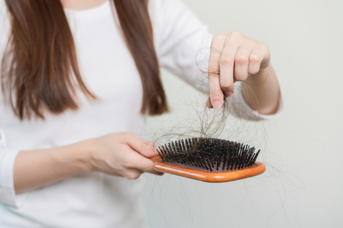 Person hält eine Haarbürste und zupft Haarbüschel heraus