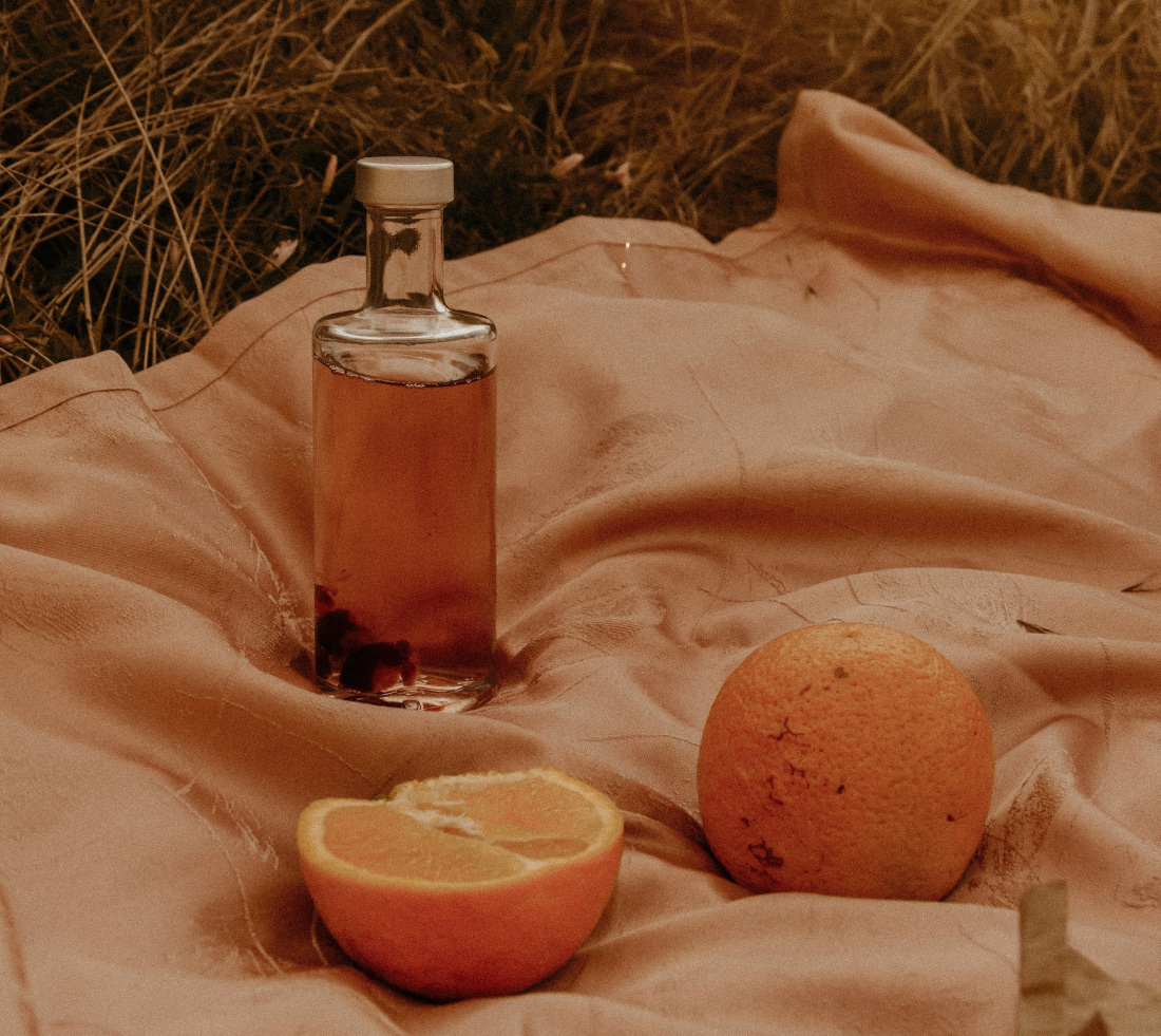 Grapefruitextrakt in Flasche, daneben eine ganze und eine aufgeschnittene Grapefruit, auf einem Tuch.